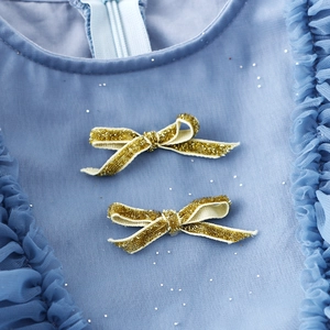 Detail of light blue girls dress featuring gold glitter bows and sparkling sequins