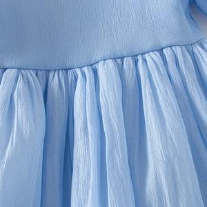 Détail de robe en tulle bleu clair pour fille avec taille haute et tissu crêpé texturé