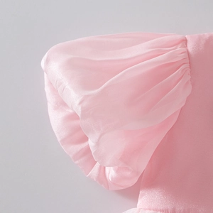 Detail of pink puff sleeves with pearlescent sheen and delicate texture on a girl's dress