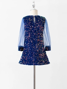 Detail of dark blue sequined girl's dress featuring sheer mesh sleeves and back cutout