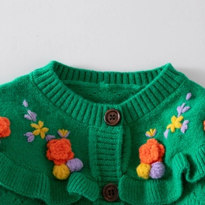 Detailed view of green knitted girls cardigan with 3D floral embroidery and wood buttons