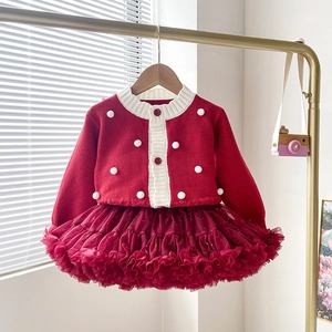 Détail du cardigan en tricot rouge à pompons et de l'ensemble jupe tutu en tulle scintillant