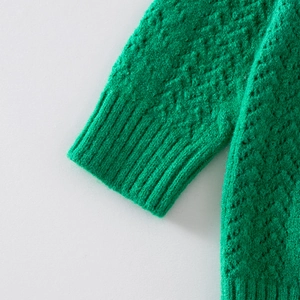 Detail of green knit sweater sleeve with diamond texture and ribbed cuff design