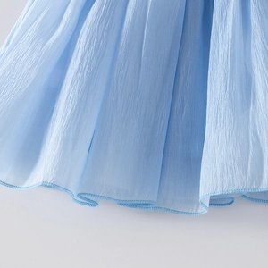 Détail du tissu en mousseline plissée bleu clair montrant les finitions de la robe