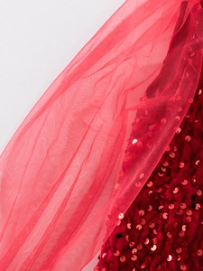 Macro detail of red sequins and layered mesh fabric on girls' long-sleeve princess dress