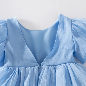 Détail d'une robe bleue pour fille avec col en V, fermeture invisible et texture crêpe