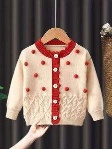 Gilet de Noël tricoté pour filles avec pompons rouges et boutons sur fond crème