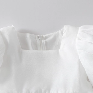 Detail of white girls' dress showing square neckline, bubble sleeves, and hidden zipper