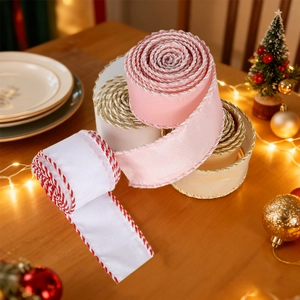 Three-color Christmas satin ribbon rolls with decorative cord edges on a festive table