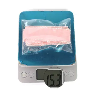 Detailed view of pink ribbon weighing 15.3g on a scale for professional packaging