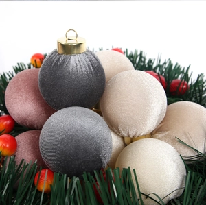 Close-up of velvet Christmas ornaments in gray and beige tones with gold caps on pine