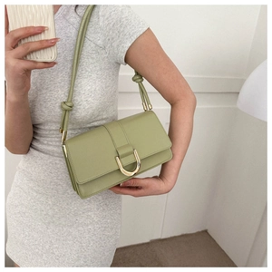 Detail of sage green shoulder bag with gold U-shaped buckle and knotted rope strap