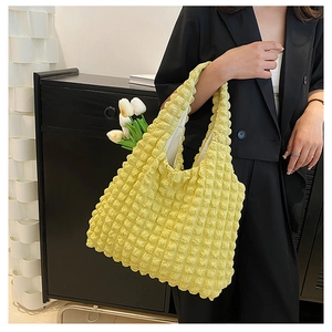 Fashionable light yellow popcorn textured tote bag carried by a model in a black suit