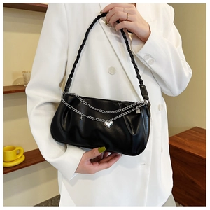 Close-up of black pleated leather underarm bag with double silver chains and heart pendant
