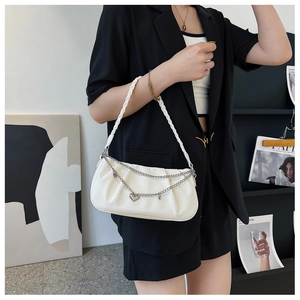 Detailed close-up of white ruched shoulder bag with heart pendant and silver chains