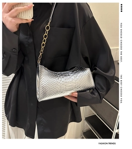 Silver snakeskin underarm bag with gold metal ring strap worn on shoulder