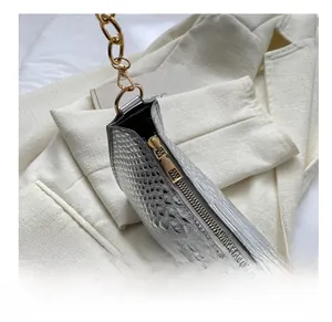 Close-up of golden smooth zipper and silver crocodile texture on the handbag