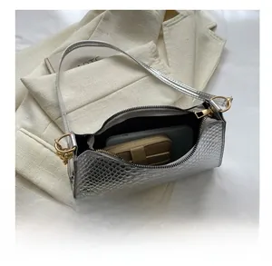 Detail showing internal capacity of silver snakeskin shoulder bag on a beige blazer