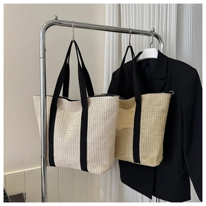 Detail of woven straw tote bag texture with black canvas handle and beige finish