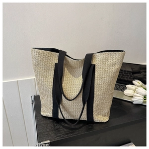 Detailed texture of straw tote bag with black straps in a minimalist lifestyle setting