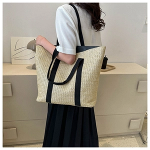 Lifestyle view of large straw tote bag with black handles on female model's shoulder