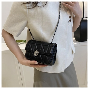 Detail of black triangular quilted leather bag with silver round metal buckle and chain strap