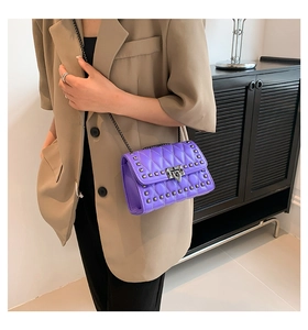 Detail of purple quilted shoulder bag featuring silver rivets and metal chain strap