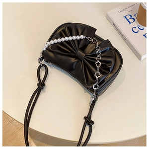 Detail of black bow handbag with faux pearl chain and metal flower decorative strap