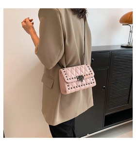 Detail of pink quilted shoulder bag with metal studs and elegant chain strap close-up