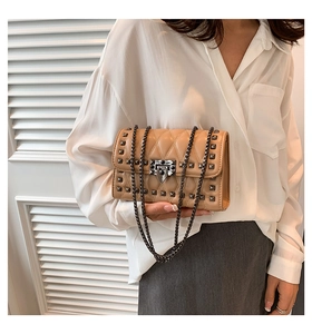 Close-up of beige quilted crossbody bag with metal studs and silver chain strap