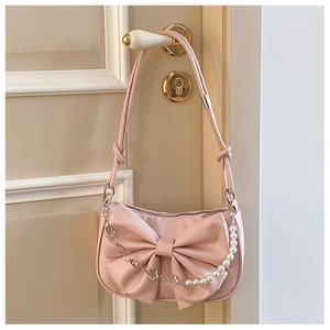 Detail of light pink bow handbag with decorative pearl and silver floral chain handle