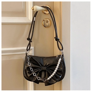 Detail of black bow shoulder bag with decorative pearl and silver flower chains