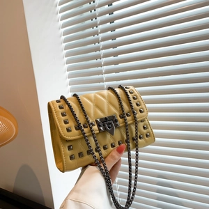 Trendy yellow crossbody bag with quilted rhombic pattern and metal studs on chain strap