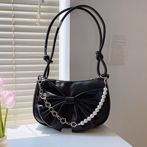 Black bow shoulder bag with floral silver chain and white pearl strap on a white table