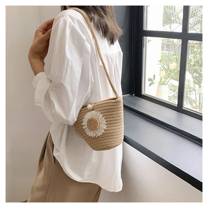 Détail du sac seau en paille tissé avec une grande marguerite blanche et perle
