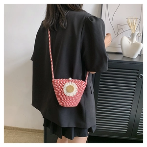 Détail du sac seau tressé rouge et blanc avec fleur de marguerite et fermoir perle