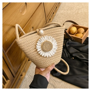 Gros plan du sac en paille tissé avec décor de marguerite et bouton en perle