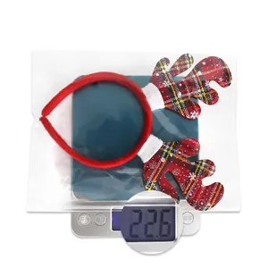 Detail view of a plaid Christmas reindeer headband placed on a digital weight scale
