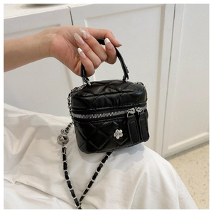 Detail of black quilted mini bag with silver chain strap and flower ornament