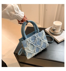 Detail der hellblauen Denim-Handtasche mit Rautensteppung, Fransenblumen und Ledergriff