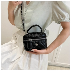 Detail of black quilted mini bag with silver camellia ornament and chain strap