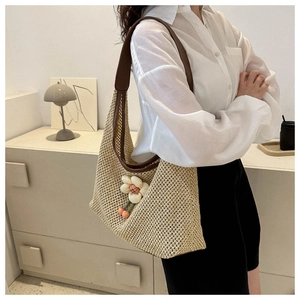 Detalle del bolso hobo de paja tejido a mano con asa de cuero y adorno de flor