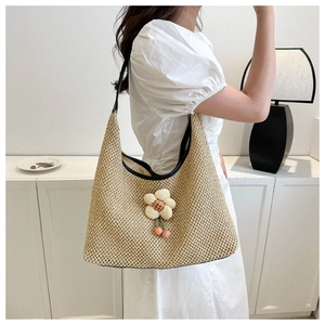 Detalle de bolsa de paja con correas de cuero negro y colgante de flor de peluche