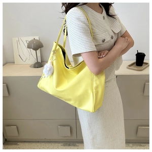 Détail du sac cabas jaune vif avec pompon en peluche blanche et finition en cuir lisse