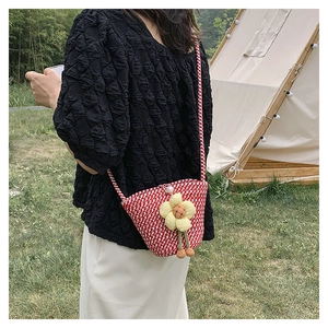 Detail of red and white checkered straw bag with large yellow fabric flower charm