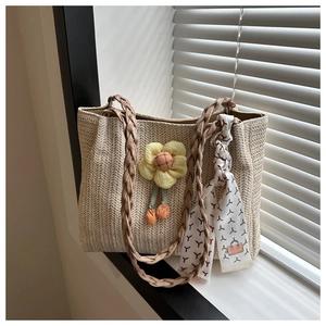 Detail of straw woven tote bag with a sunflower charm and printed scarf accessory