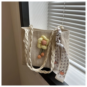 Close-up of beige woven tote bag with sunflower charm and patterned silk scarf handle