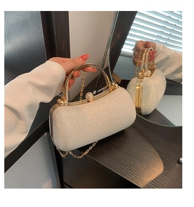 Detail of white sequin evening bag featuring a gold metal handle and chain strap
