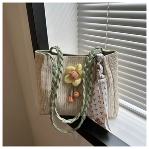 Detail of straw tote bag with green handles, sunflower charm and floral silk scarf