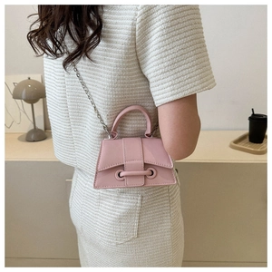 Pink mini leather crossbody bag with metal chain strap shown on a minimalist interior surface